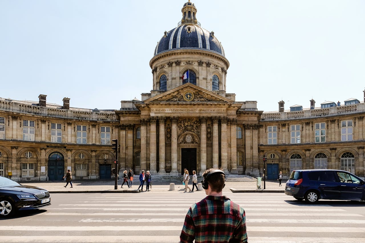 Front view of the historic Institut de France with people crossing the street in Paris.